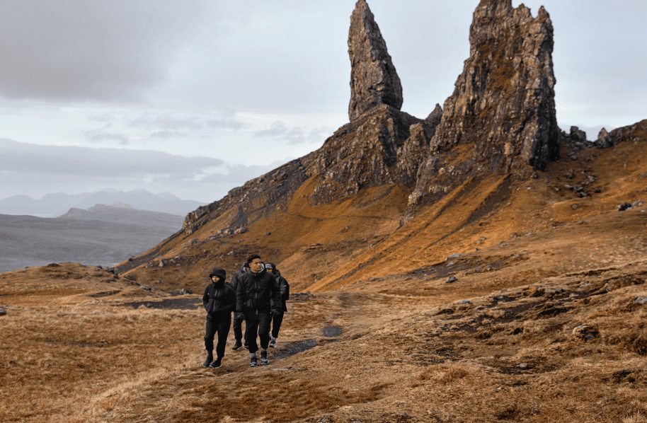 Three people hiking with big rocks in the background.