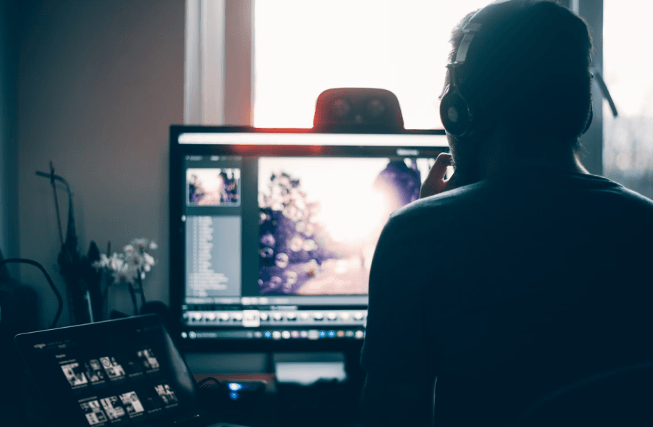 A person looking at a computer with very little lighting in the room.