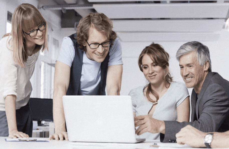 A group of people standing in front of a computer.