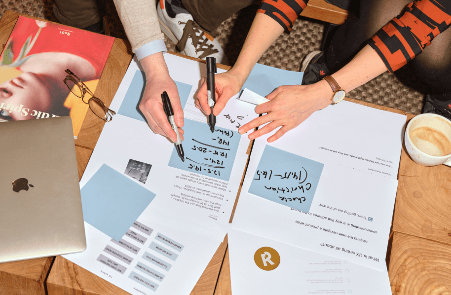 Multiple people making notes on some documents laid on a table.