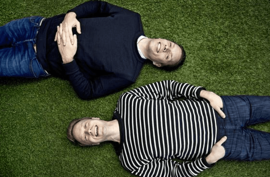 Two people lying parallel on grass.